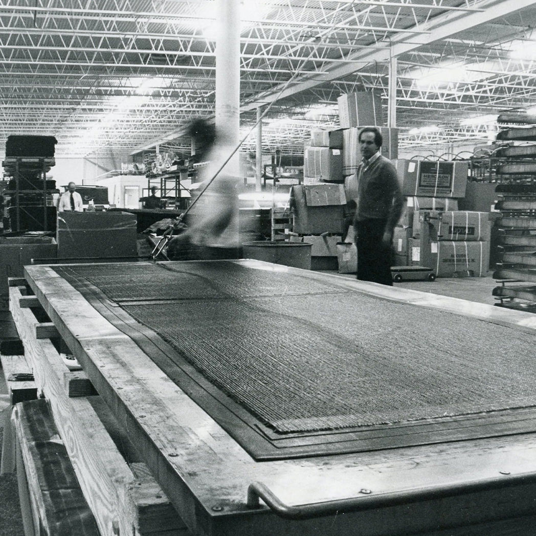 Black and white image of a factory where the original WaterHog mat was created and made by Robb Andersen. 