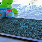 Leafy textured green doormat by a pool with inflatable toys in the background
