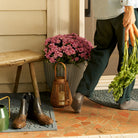 Women carrying carrots from her garden inside, walking over a bluestone Boxwood runner and half-round doormat, with her muddy boots in the mat.