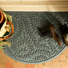 Overhead of half-round Boxwood doormat at a door with a pair of muddy boots thrown on top by the gardening tool bag.