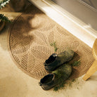 A quality WaterHog luxury half-round-doormat in a light brown camel with a pair of grass covered boots on the mat.