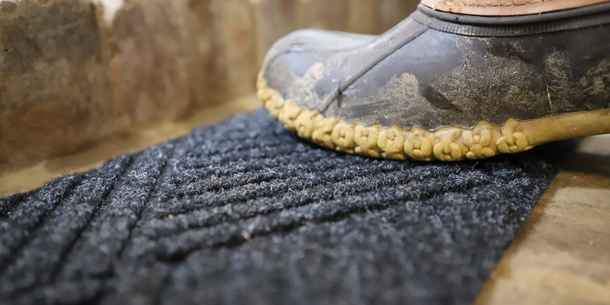 Zoomed in image of muddy boot stepping on a WaterHog Diamonds stair tread mat. 