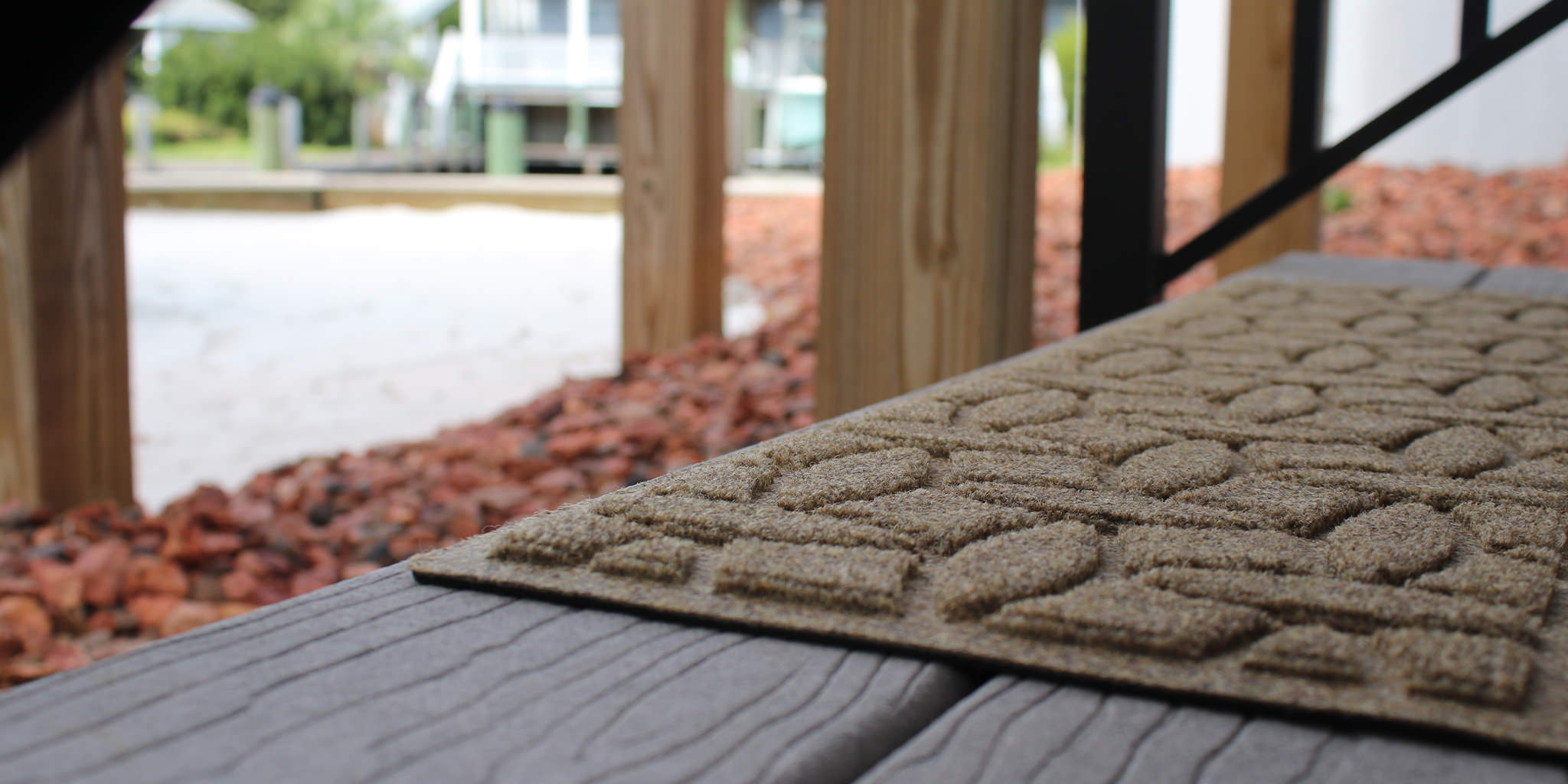 Zoomed in image of a light tan WaterHog Luxe stair tread in Ellipse on an outdoor porch step. 