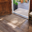 Medium WaterHog Argyle doormat placed just inside a front door on light brown wooden floors.