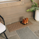 WaterHog Boot Tray mat in the classic Argyle design on a cover porch with a pair of rubber bottom boots on top for dirt control.