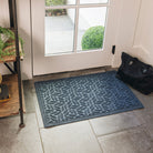 Genuine deep blue WaterHog indoor/outdoor doormat placed inside a home at a front or side door with a bag/purse placed beside it. 