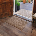 An entrance way with two camel colored WaterHog mats with a fallen leaf design. A large 3x5 version of the WaterHog Mat placed outdoors, while a 2x3 size is placed inside.