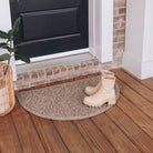 A semi circular WaterHog doormat in a tan color with a fallen leaf design placed in front of a ingle door entrance way.