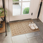 A tan WaterHog High Rise durable doormat with an elevated chevron-like design displayed on tile floor inside an entrance way and shoes placed on top.