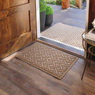 WaterHog Lattice 2x3 indoor/outdoor mat in tan, featuring a crisscross geometric design, displayed on wood flooring in front of a single door inside, with a large version outside.