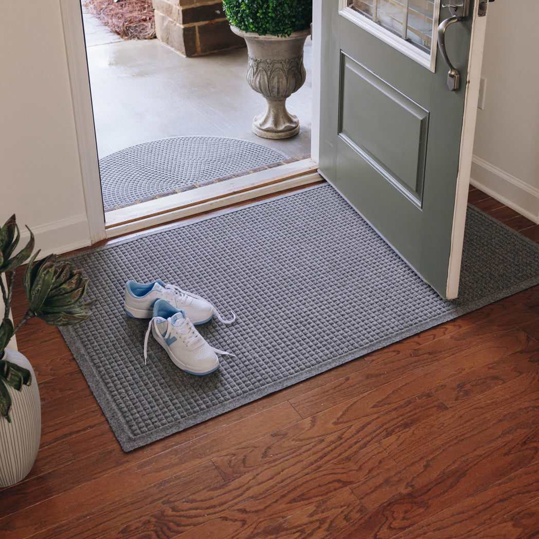 An inside view of a indoor WaterHog Squares mat at the entrance of a home with a matching Half Round doormat outside for double the floor protection.