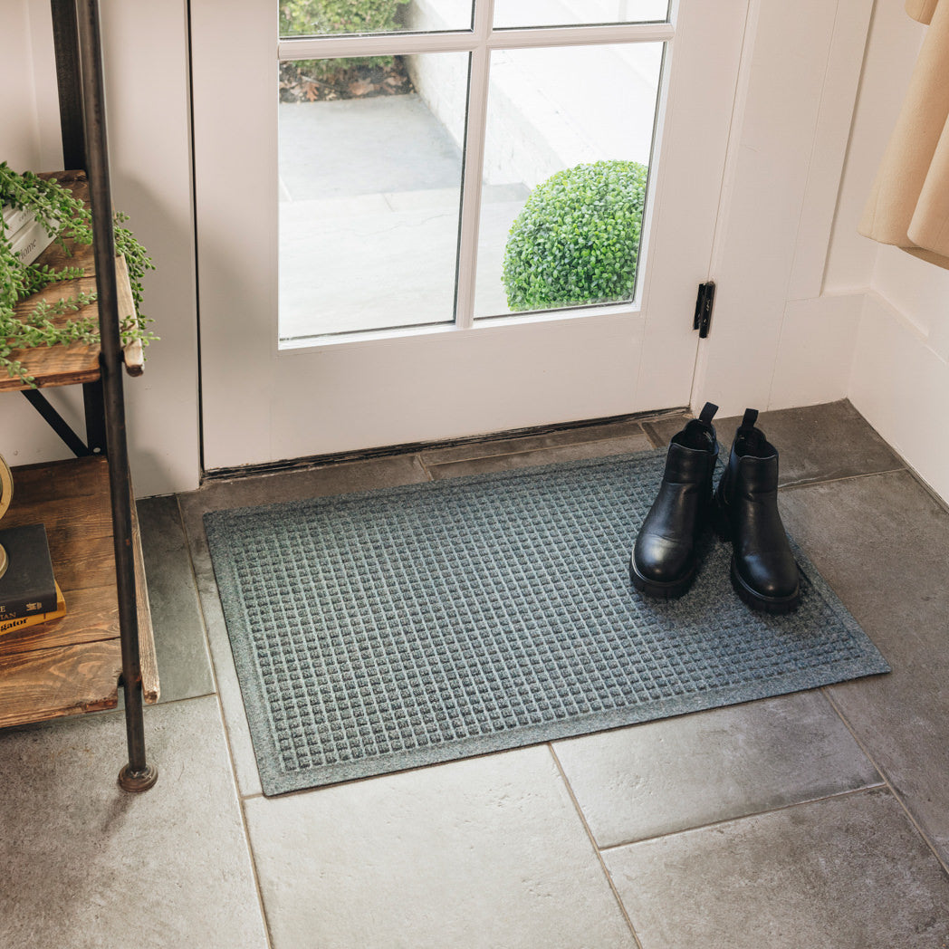 A 2x3 WaterHog Squares doormat in a creamy light blue located at a side entrance for dirt and moisture trapping.