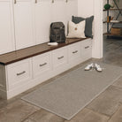 A medium WaterHog Squares runner doormat placed in a large mudroom to help protect floors from where the family sits to take off dirty shoes or jackets.