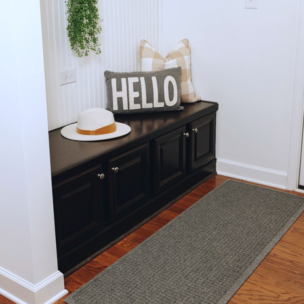 A WaterHog Squares runner doormat at the side entrance of a home to scrape and trap dirt and moisture below shoe level to help prevent tracking throughout the house.