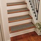 Medium grey WaterHog Stair Treads place on a set of indoor, red wood stairs to help for added traction and protect floors from scuffing damage.