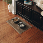 A WaterHog pet mat featuring a subtle wave design in a neutral brown holding two stainless steel bowls helping to keep the feeding area clean and organized.