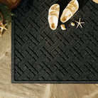 Corner overhead of WaterHog Lattice doormat's charcoal surface that's collected sand from the beach.