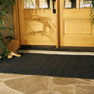 An extra-large 4x6 Lattice charcoal doormat on stone flooring outside close double doors.