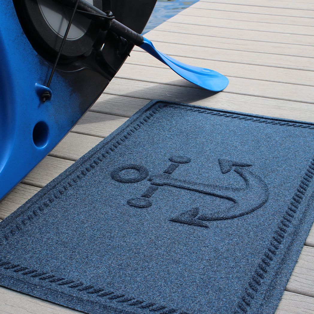 WaterHog Ships Anchor outdoor doormat placed outside on a dock next to water to help provide grip and traction in slippery areas.