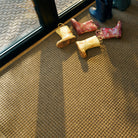 Overhead of a camel WaterHog Squares extra large doormat with a kids dirt boots thrown on top.