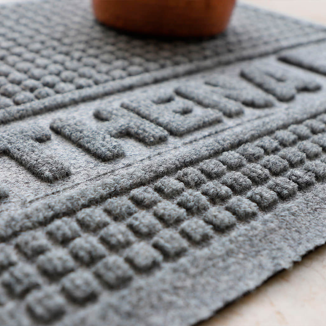 Close-up shot of WaterHog Square bi-level surface and personalized name in the color grey perfect for pet bowls where food and water can spill. 