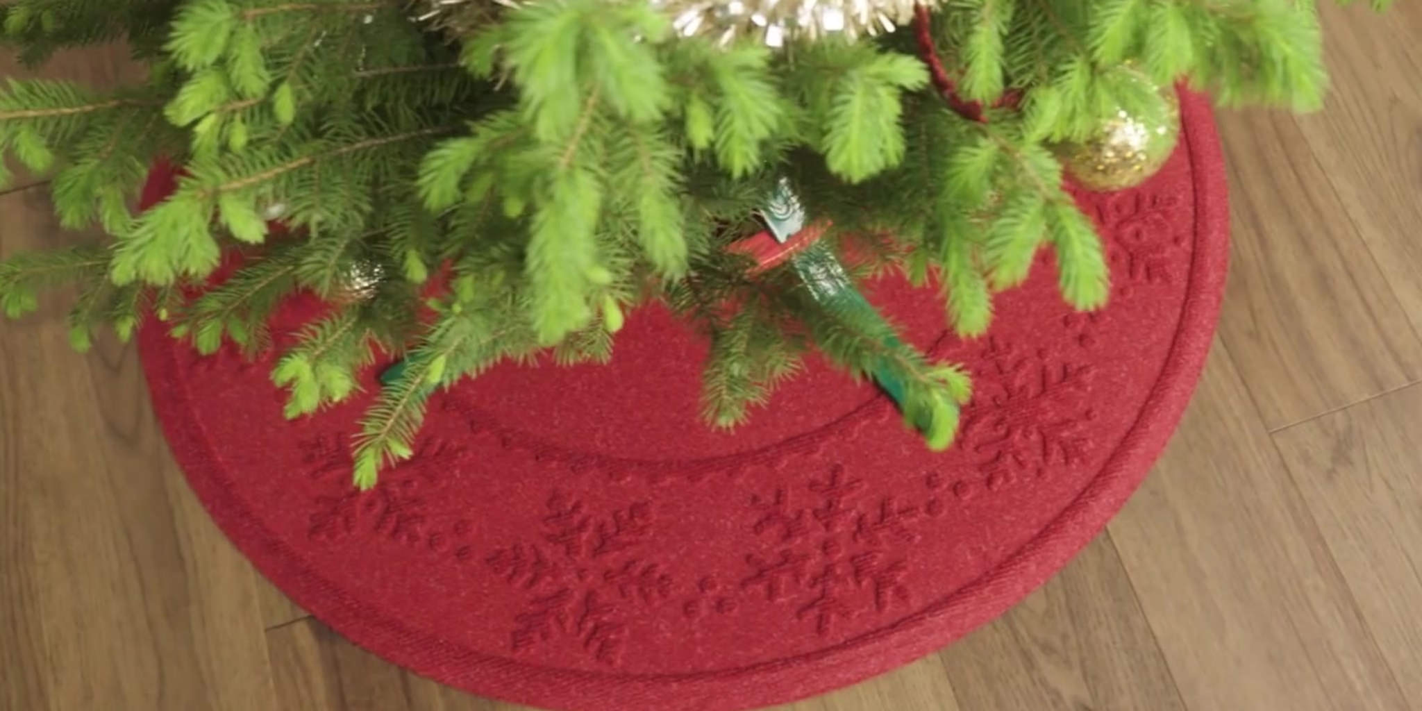 Overhead view of a Christmas tree on a WaterHog bright red Tree Skirt for protecting the wooden floor from water damage