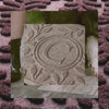 Close-up of a C-initialed WaterHog personalized doormat, overlaid on a blurred outdoor setting.
