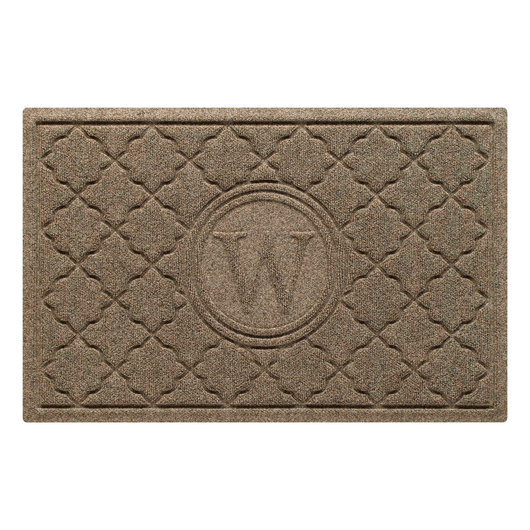 Isolated image of a medium outdoor WaterHog Bombay Monogrammed Doormat that features a classic repeating geometric pattern with an encircled letter placed in the center; shown in a light brown camel color.