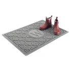 Isolated image of a medium size WaterHog Bombay Monogrammed Doormat with a pair of red women's rain boots on top for size reference; shown in medium grey color and the letter W.