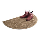 Isolated WaterHog Boxwood half-round doormat in camel with a pair of pink rubber boots in the doormat.