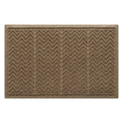 This image features a rectangular WaterHog doormat in a neutral brown or tan color. The mat has a distinct zigzag or chevron pattern, divided into vertical sections, designed to effectively scrape dirt and absorb moisture. It is surrounded by a reinforced border, which helps contain water and debris, preventing spills onto surrounding floors. The textured surface is made from recycled synthetic fibers with a rubber backing, making it suitable for high-traffic areas.