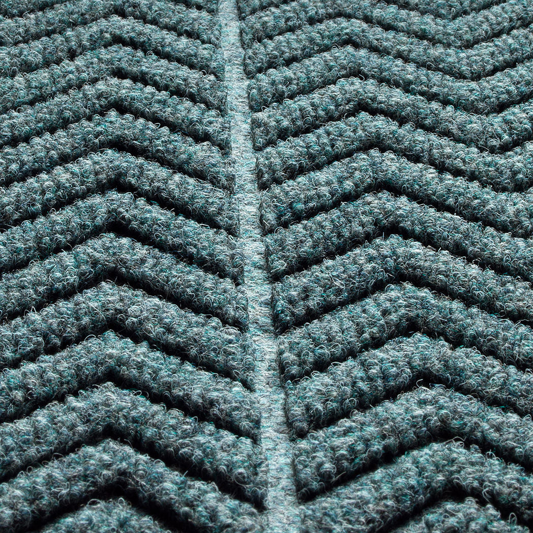 Zoomed in view of WaterHog Chevron doormat's surface detailing the bi-level zig ag pattern made of recycled PET surface in fiber colors blue, grey, and green 