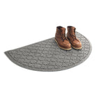 Isolated WaterHog Cordova half-round doormat in medium grey with a pair of brown leather boots in the doormat.