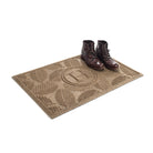 The OG WaterHog 2x3 Deanna monogram doormat in camel with boots placed on top on a white background.