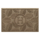 A luxury WaterHog Deanna medium-sized monogram doormat in a light tan leafy design on an eco-friendly surface.