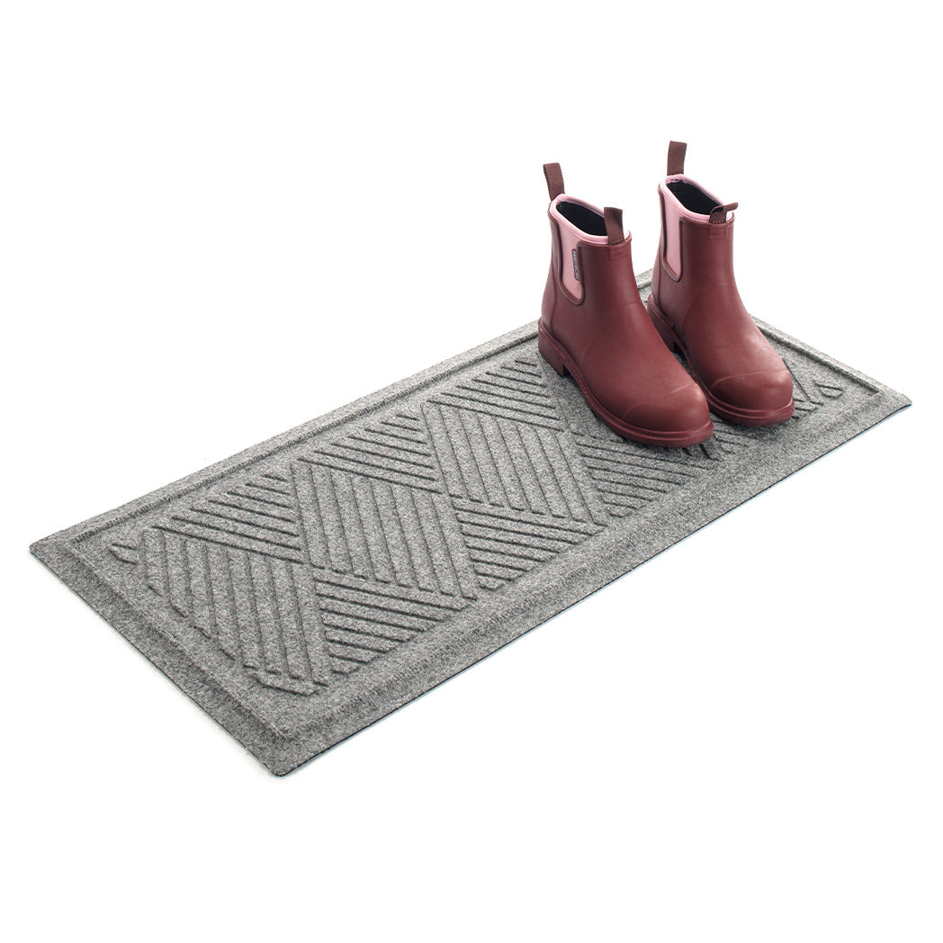 Angled WaterHog 2x3 boot tray with a pair of pink rubber boots in the doormat on a white background.