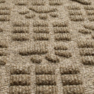 Detail shot of WaterHog's Dog Paw Squares all-weather mat in a light tan/golden color, showing its dirt-trapping, bi-level surface. 