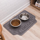 A WaterHog Drool Hog bowl mat personalized with the name Bella, with dog food dishes placed on top on the grey mat.