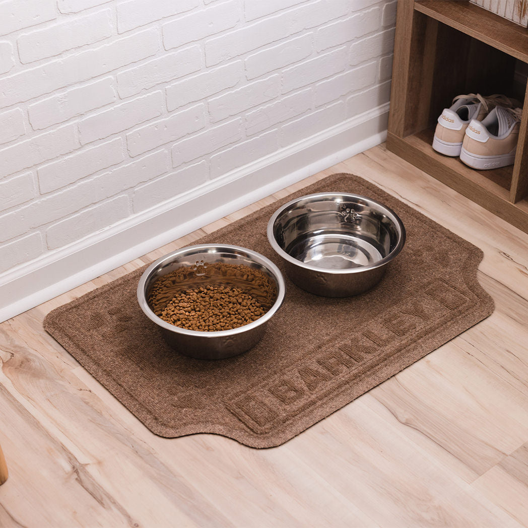 A food and water dish on top of a large Drool Hog bowl mat that's personalized with the name Barkley, located in a mud room.