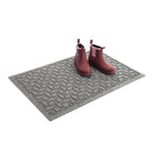 A premium WaterHog 2x3 Ellipse all-weather doormat in grey with a pair of rubber boots placed on top.