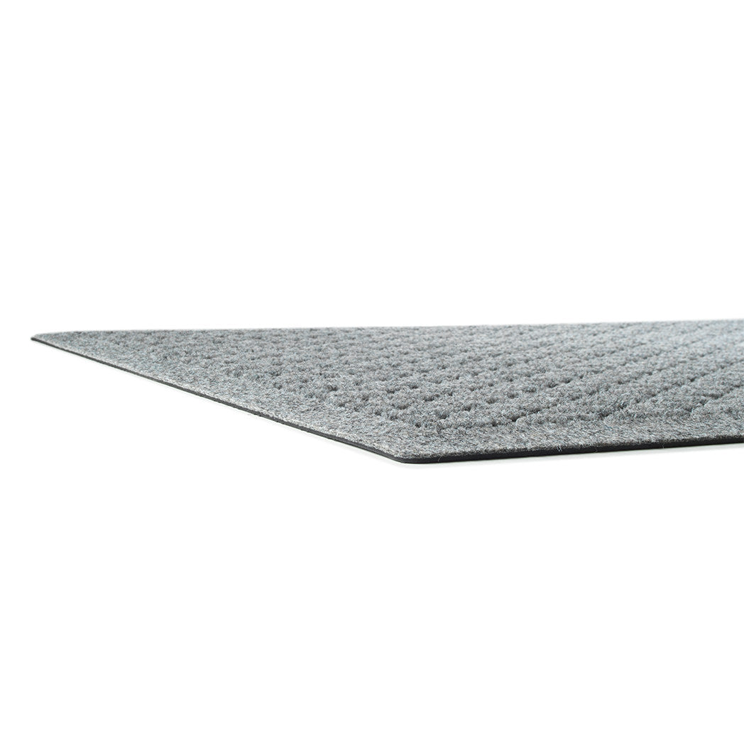 A side shot of a WaterHog Hampton low-profile mat in light grey with a carpeted edge and rubber backing.