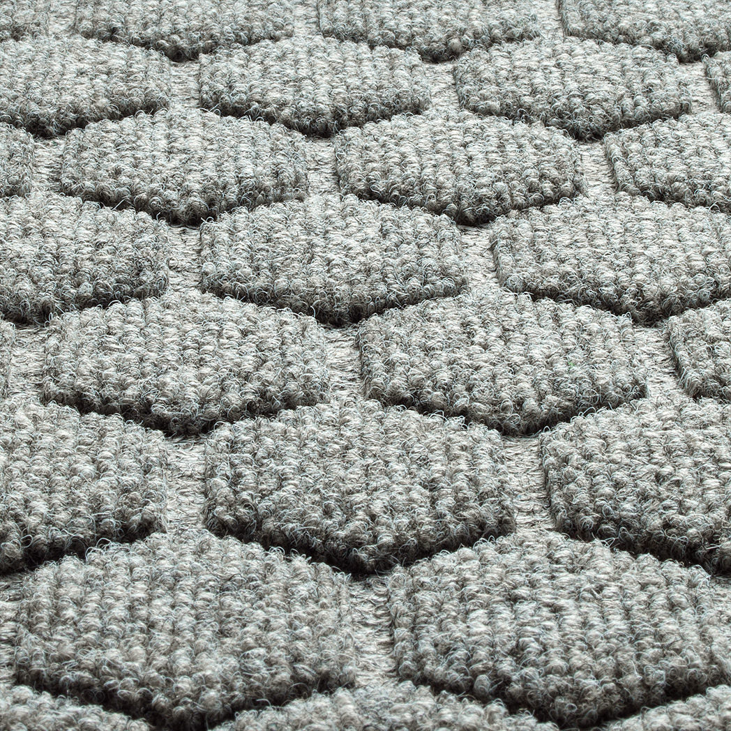 A close-up shot of the WaterHog Honeycomb all-weather doormat in light grey, displaying the carpeted fibers that form the raised design.