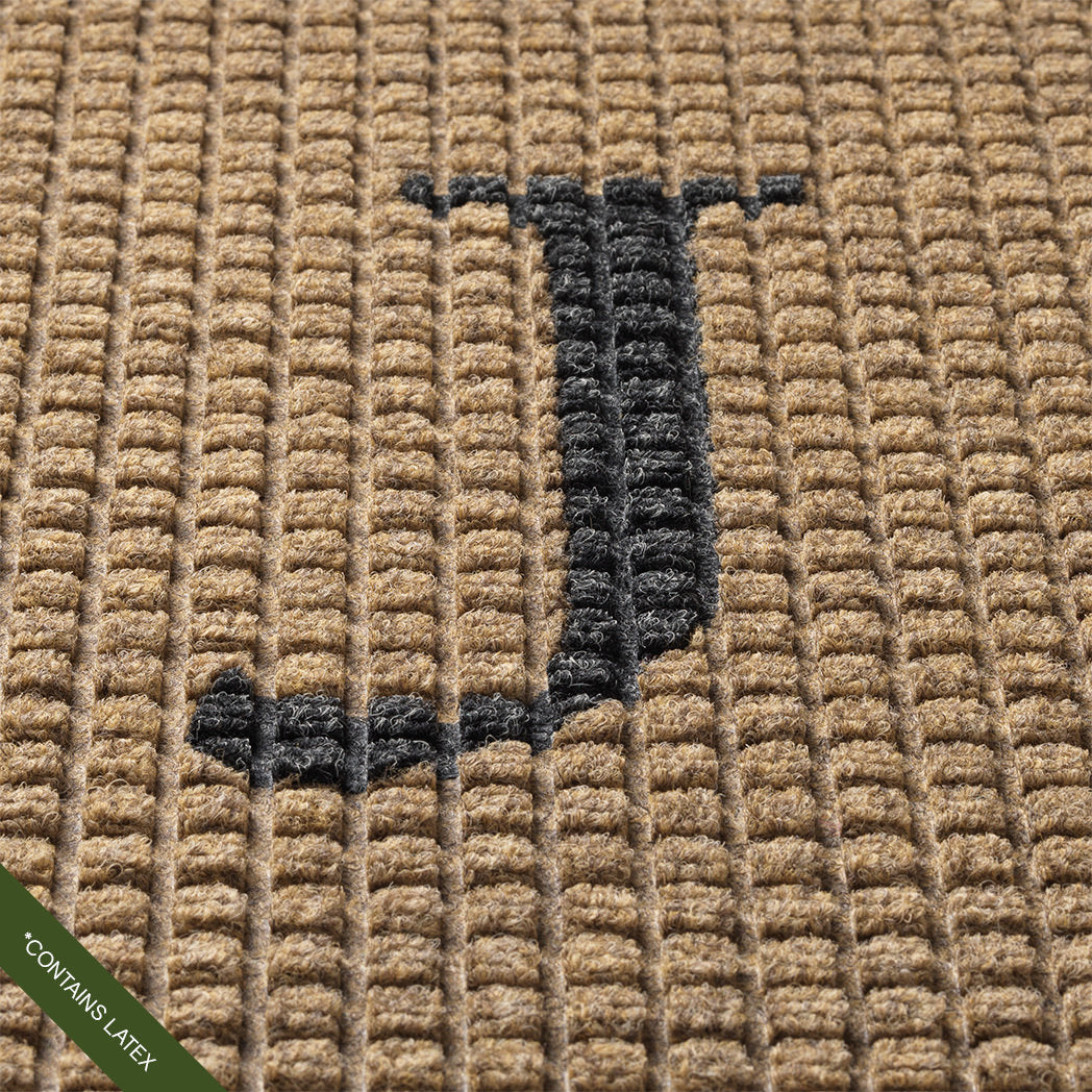 Close-up of the hand-cut and inlaid serif 'J' in charcoal on a tan WaterHog squares doormat; latex disclaimer