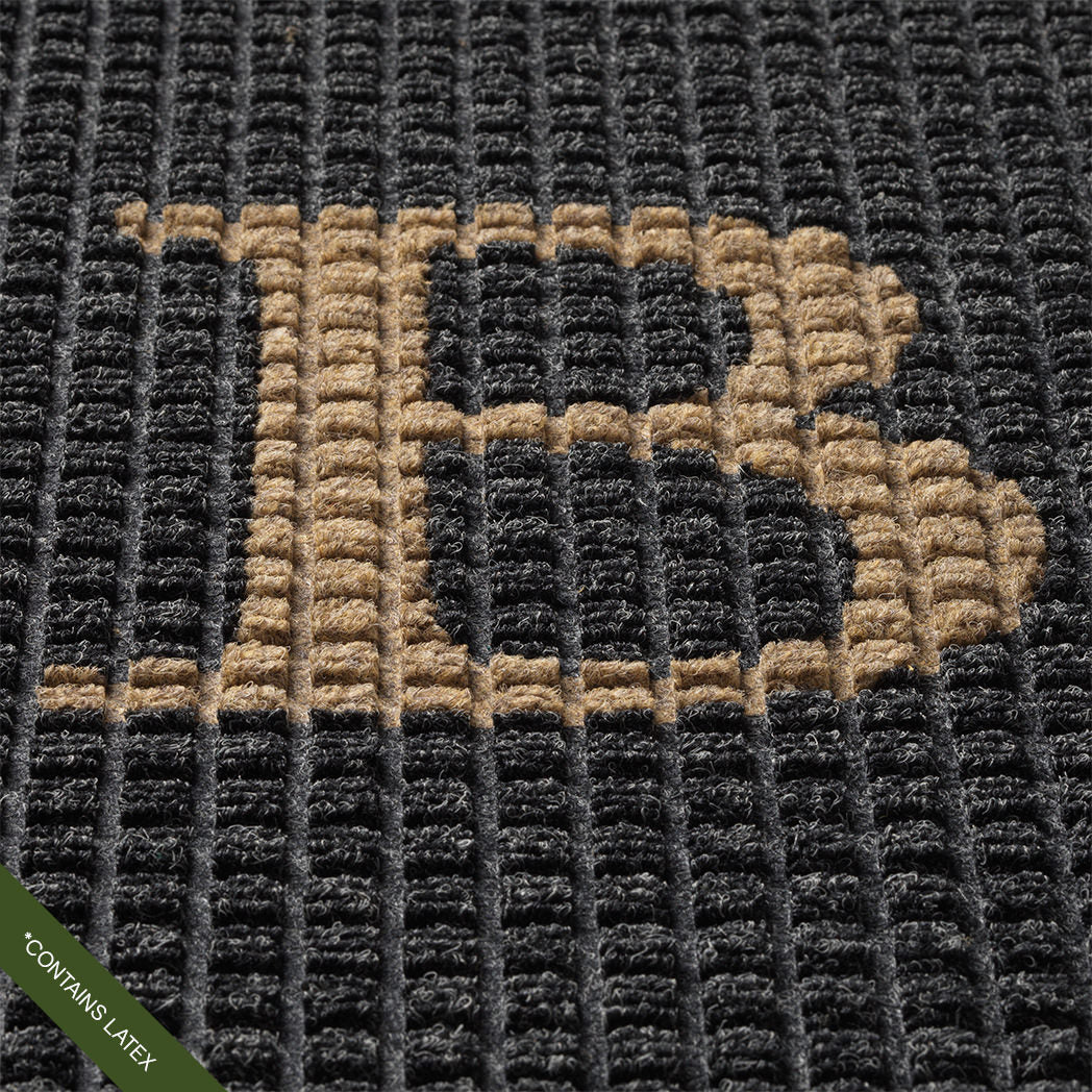 Close-up of the hand-cut and inlaid serif 'B' in camel on a charcoal WaterHog squares doormat; latex disclaimer