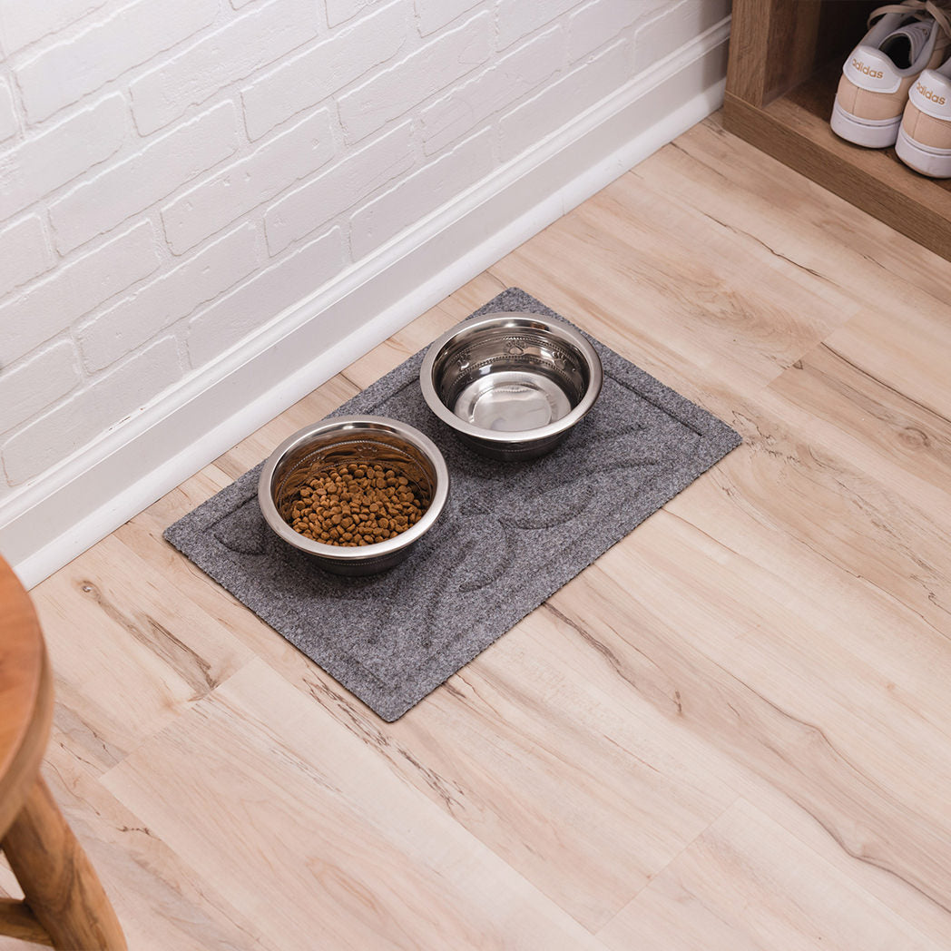 Cat food on top of a small, medium grey Kitty Face mat for floor protection from the water and food.