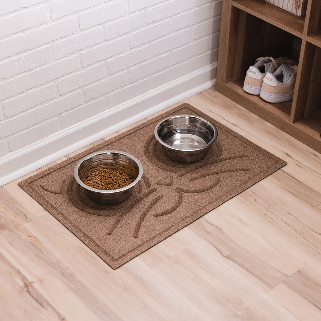 Cat food and water dishes on top of a camel Kitty Face bowl mat for protection from pet spills and accidences