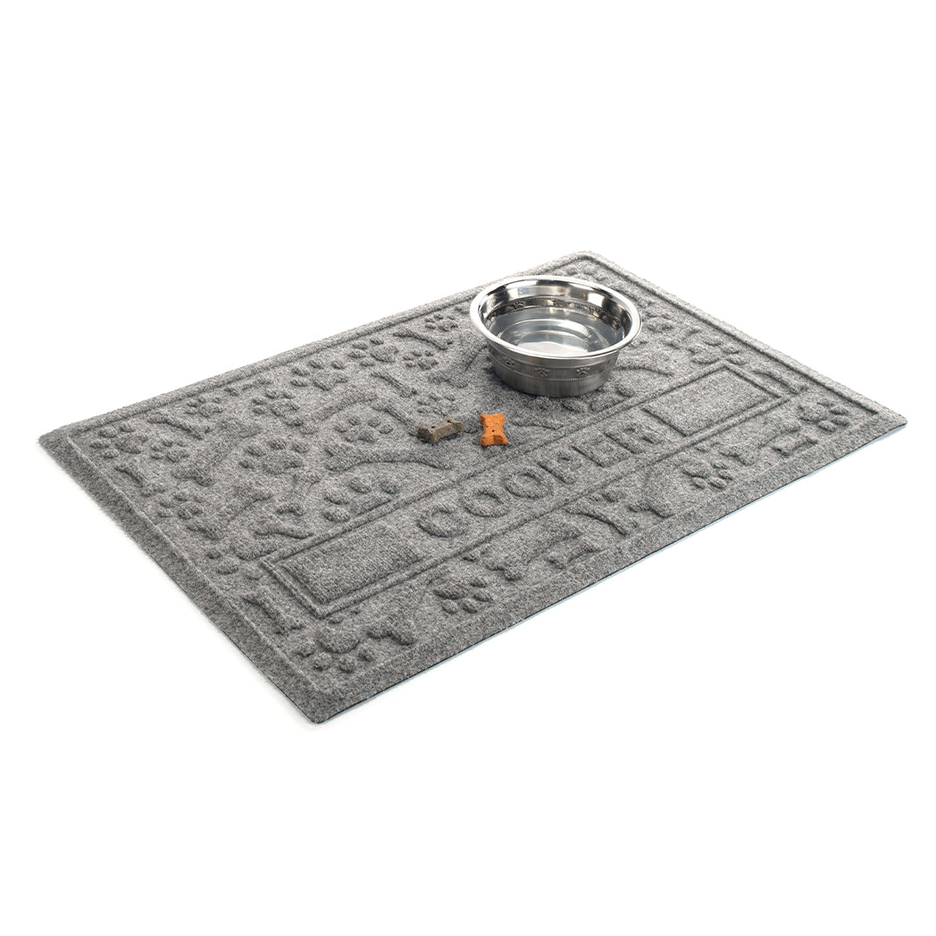 Angled WaterHog Paws & Bones personalized bowl mat in a 2x3, camel mat with a water dish and dog treats for size reference.