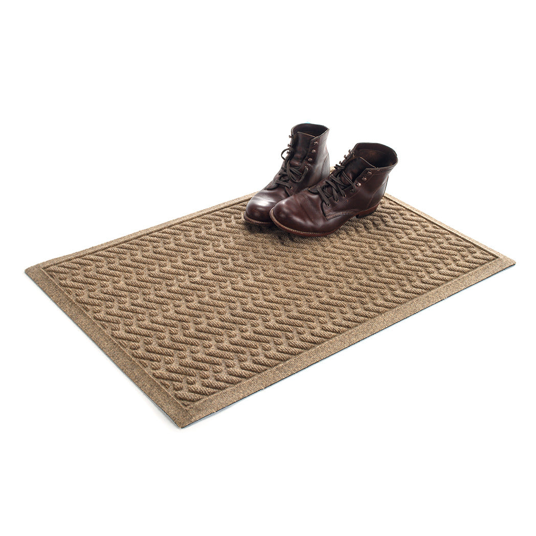 The premium WaterHog 2x3 all-weather Sentry doormat in camel with a pair of boots placed on top on a white background.