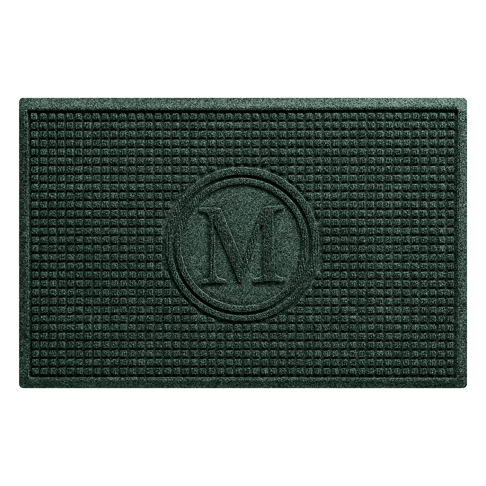 An overhead of a WaterHog Squares doormat monogrammed with an M in the center with a circle around it, shown in a deep green durable surface.