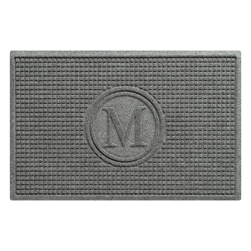 Overhead of a WaterHog Squares all-weather doormat monogrammed with the letter M in a light grey, fade-resistant surface, backed by durable rubber.